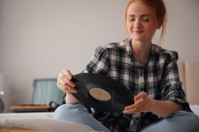 Young woman with vinyl disc for turntable in bedroom Photo of Young woman with vinyl disc for turntable in bedroom