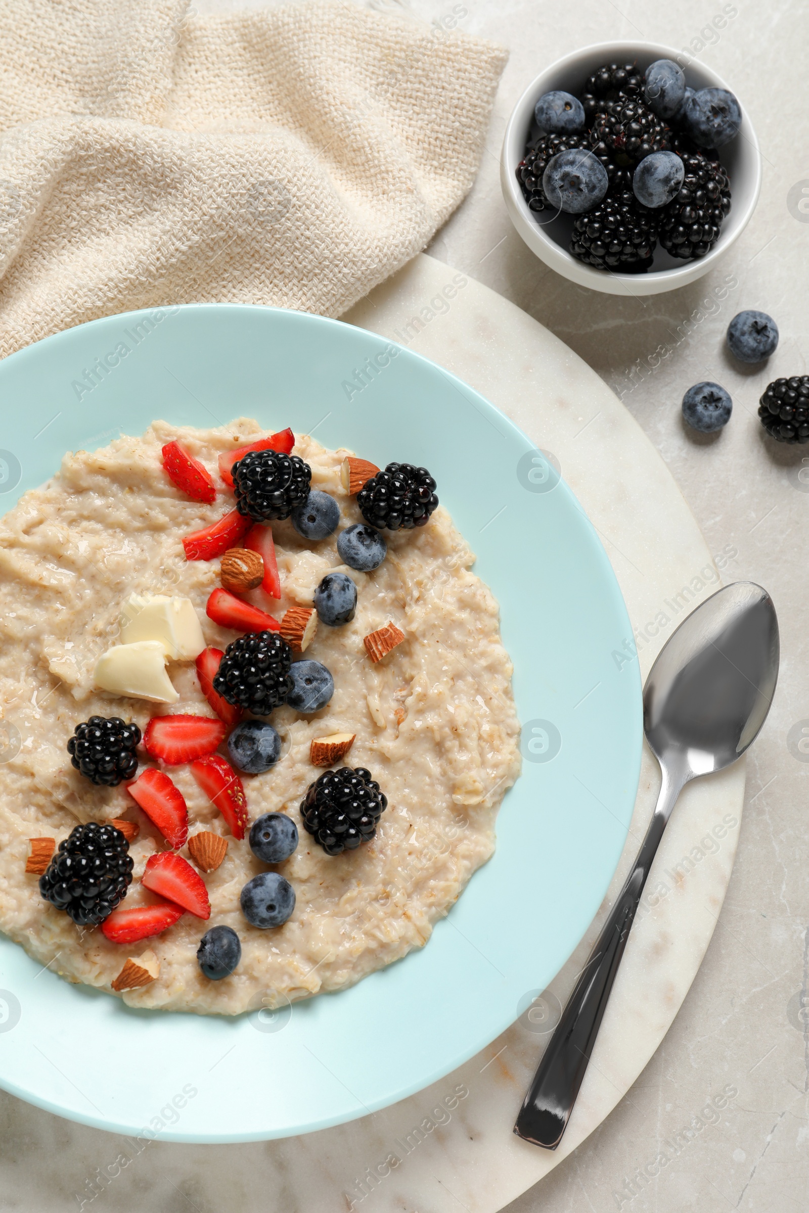 Tasty oatmeal porridge with berries and almond nuts served on light table, flat lay Photo of Tasty oatmeal porridge with berries and almond nuts served on light table, flat lay