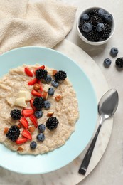 Tasty oatmeal porridge with berries and almond nuts served on light table, flat lay Photo of Tasty oatmeal porridge with berries and almond nuts served on light table, flat lay
