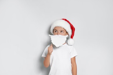 Cute little boy with Santa hat and white beard prop on white background. Christmas celebration Image of Cute little boy with Santa hat and white beard prop on white background. Christmas celebration