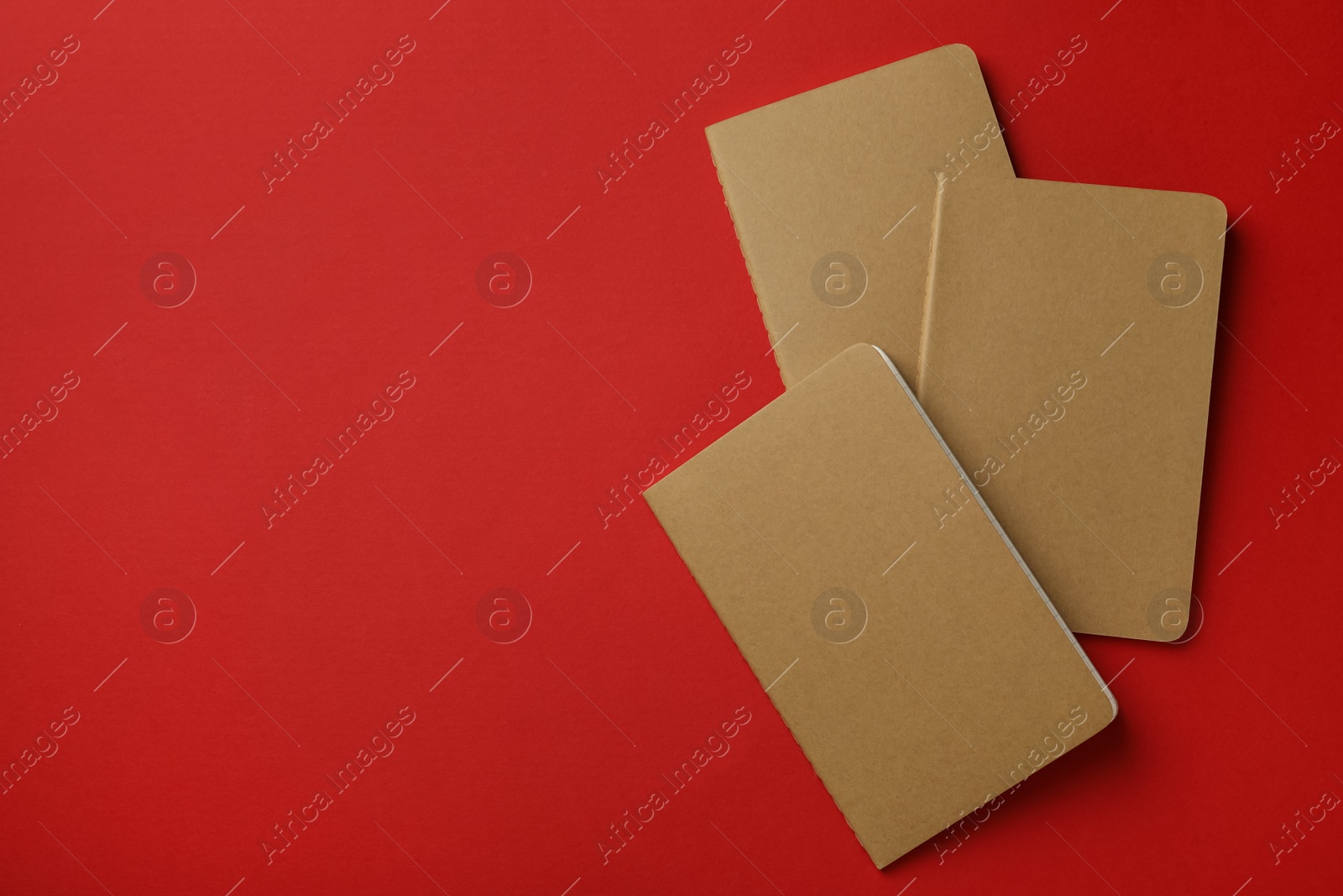 New stylish kraft planners on red background, top view. Space for text Photo of New stylish kraft planners on red background, top view. Space for text