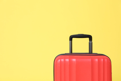 Photo of Stylish red suitcase on yellow background. Space for text