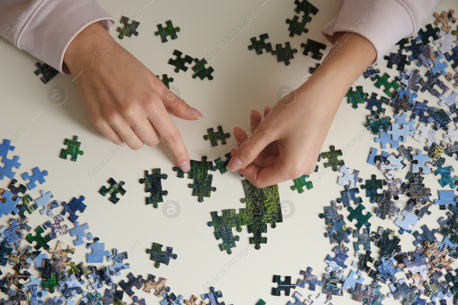 Young woman playing with puzzles at table, top view Photo of Young woman playing with puzzles at table, top view