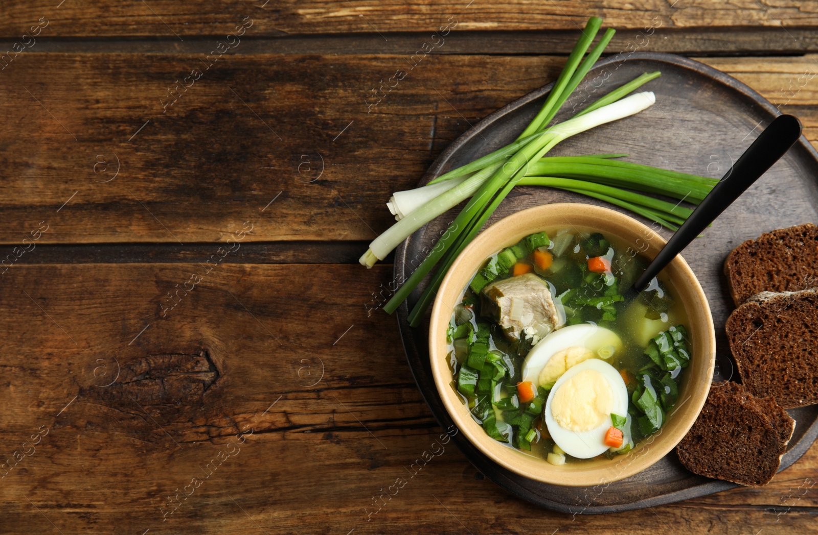 Delicious sorrel soup with meat and eggs served on wooden table, flat lay. Space for text Photo of Delicious sorrel soup with meat and eggs served on wooden table, flat lay. Space for text