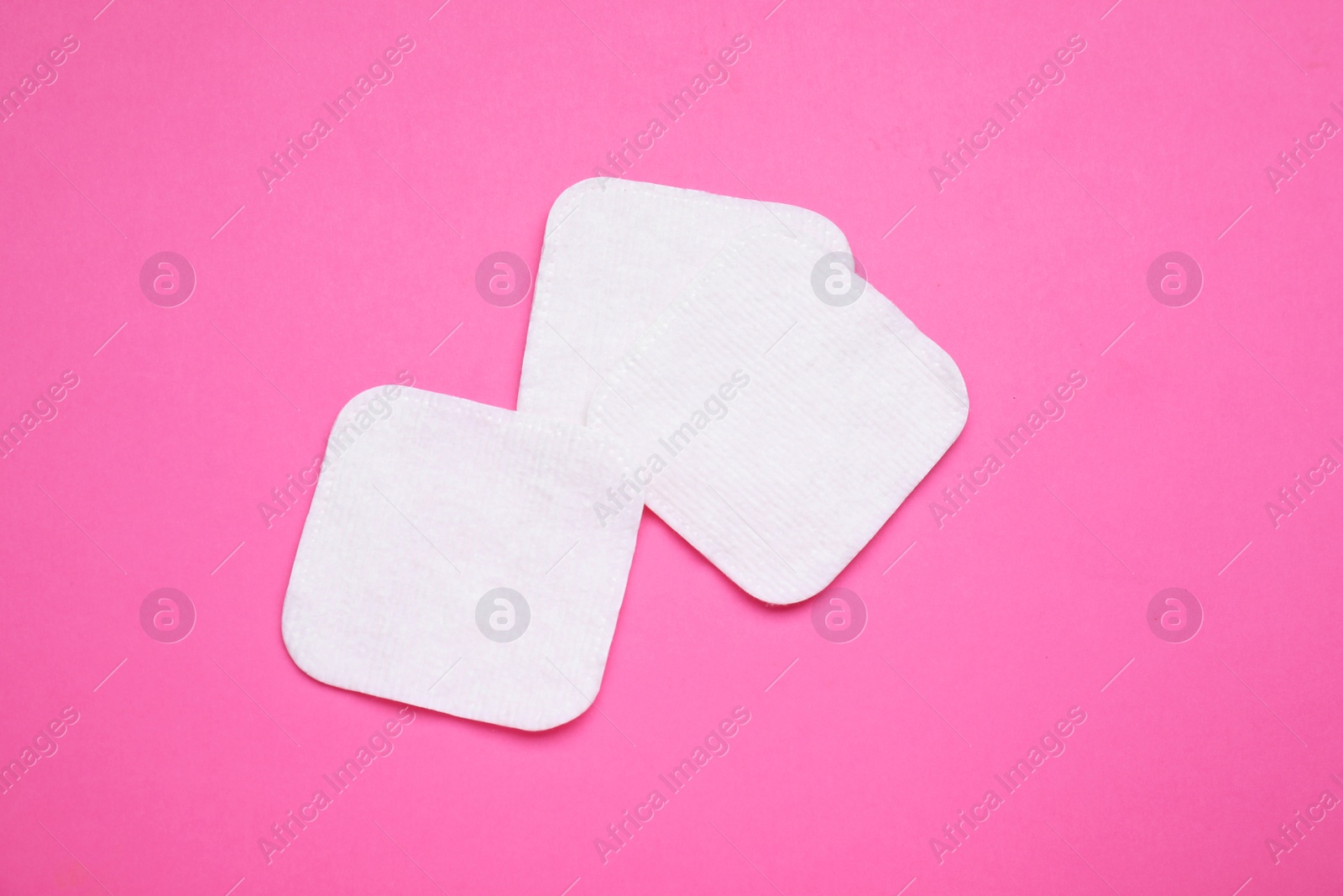 Cotton pads on pink background, flat lay Photo of Cotton pads on pink background, flat lay