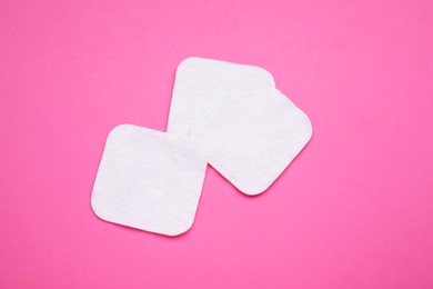 Cotton pads on pink background, flat lay Photo of Cotton pads on pink background, flat lay