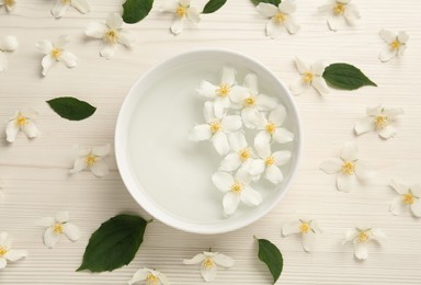 Bowl with water and beautiful jasmine flowers on white wooden table, flat lay Photo of Bowl with water and beautiful jasmine flowers on white wooden table, flat lay