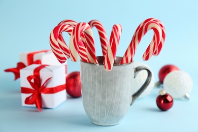 Christmas candy canes in cup on light blue background Photo of Christmas candy canes in cup on light blue background