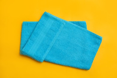 Folded light blue beach towel on yellow background, top view Photo of Folded light blue beach towel on yellow background, top view