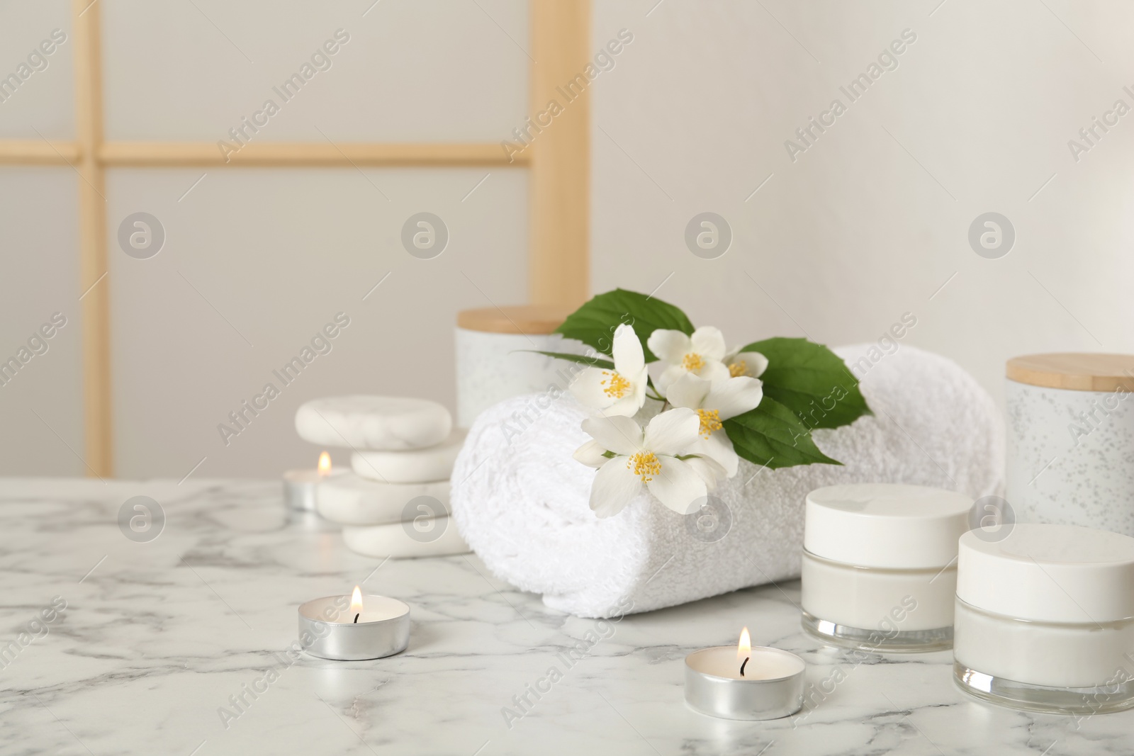 Composition with beautiful jasmine flowers and skin care products on white marble table indoors, space for text Photo of Composition with beautiful jasmine flowers and skin care products on white marble table indoors, space for text
