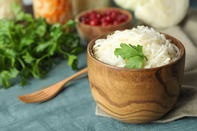 Photo of Tasty fermented cabbage on blue wooden table, closeup