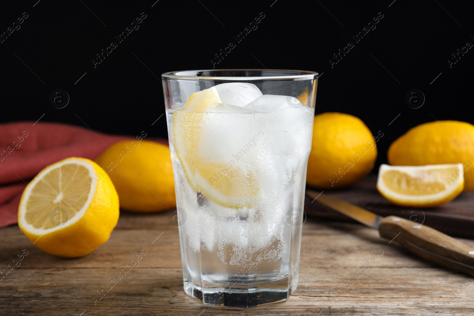 Soda water with lemon slices and ice cubes on wooden table Photo of Soda water with lemon slices and ice cubes on wooden table