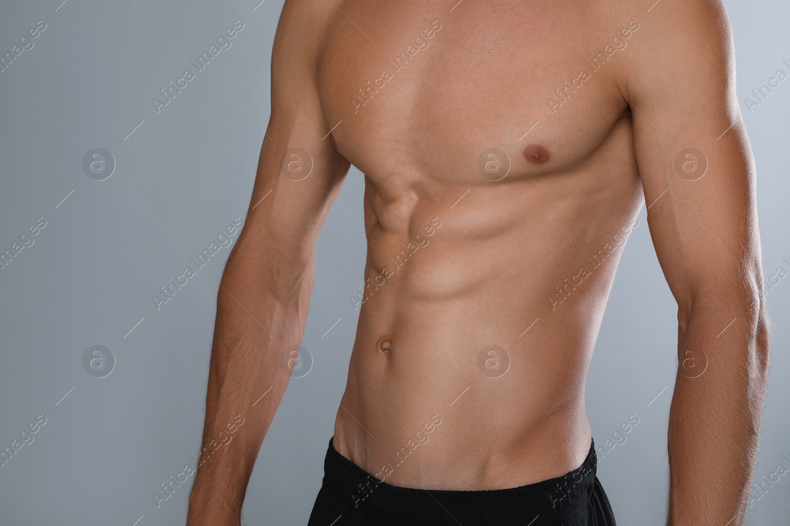 Shirtless man with slim body on grey background, closeup Photo of Shirtless man with slim body on grey background, closeup