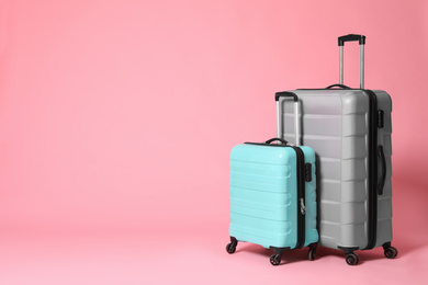Photo of Stylish grey and turquoise suitcases on pink background. Space for text