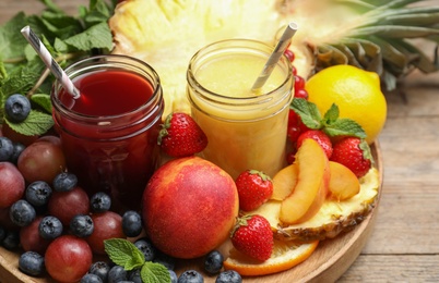 Delicious colorful juices in glasses and fresh ingredients on wooden table Photo of Delicious colorful juices in glasses and fresh ingredients on wooden table