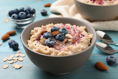 Tasty oatmeal porridge with toppings on light blue wooden table Photo of Tasty oatmeal porridge with toppings on light blue wooden table