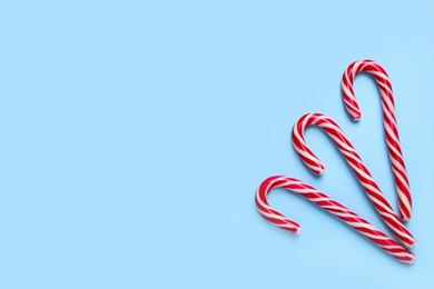 Sweet Christmas candy canes on light blue background, flat lay. Space for text Photo of Sweet Christmas candy canes on light blue background, flat lay. Space for text