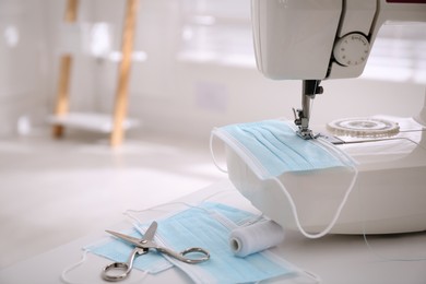 Sewing machine with disposable face mask on table indoors, space for text Photo of Sewing machine with disposable face mask on table indoors, space for text
