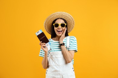 Happy female tourist with ticket and passport on yellow background Photo of Happy female tourist with ticket and passport on yellow background
