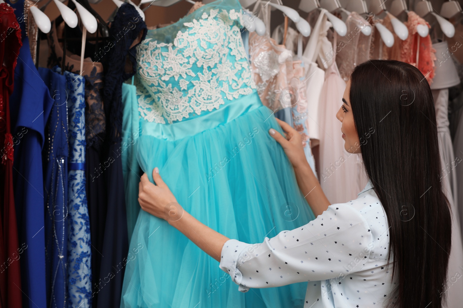Woman choosing dress in rental clothing salon Photo of Woman choosing dress in rental clothing salon