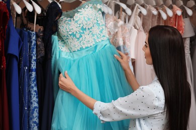 Woman choosing dress in rental clothing salon Photo of Woman choosing dress in rental clothing salon