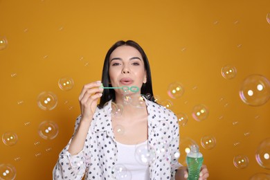 Young woman blowing soap bubbles on yellow background Photo of Young woman blowing soap bubbles on yellow background