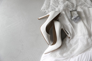 Wedding dress, white high heel shoes and ring on grey background, flat lay. Space for text Photo of Wedding dress, white high heel shoes and ring on grey background, flat lay. Space for text