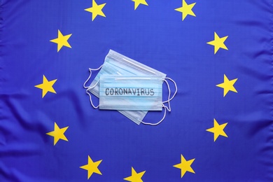 Photo of Protective masks on European Union flag background, top view. Coronavirus outbreak