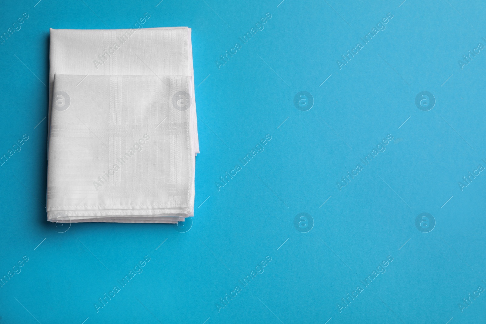 Stylish white handkerchiefs on light blue background, flat lay. Space for text Photo of Stylish white handkerchiefs on light blue background, flat lay. Space for text