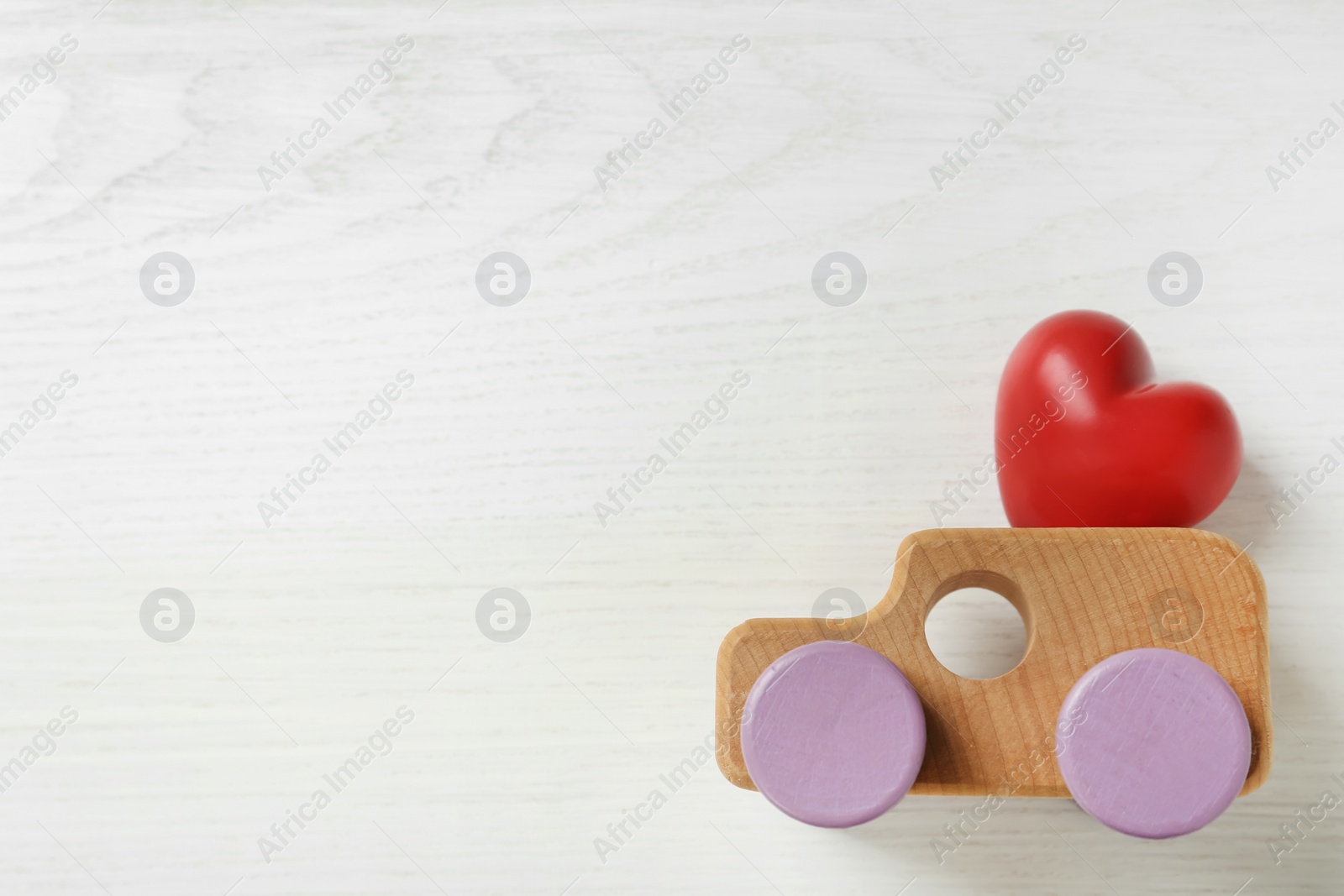 Red heart and wooden toy car on white background, flat lay with space for text. Happy Valentine's Day Photo of Red heart and wooden toy car on white background, flat lay with space for text. Happy Valentine's Day