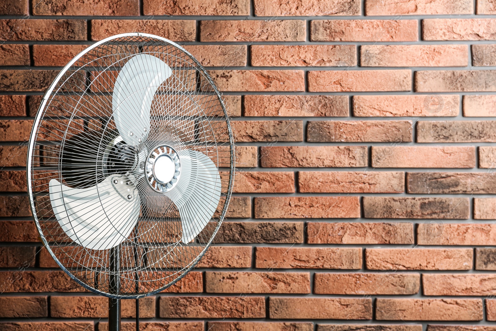 Electric fan near brick wall, space for text. Summer heat Photo of Electric fan near brick wall, space for text. Summer heat