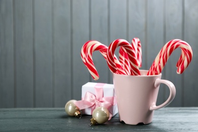 Many sweet candy canes in cup, gift box and Christmas decor on grey wooden table. Space for text Photo of Many sweet candy canes in cup, gift box and Christmas decor on grey wooden table. Space for text