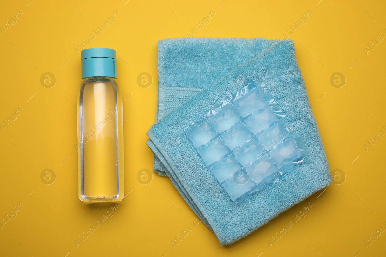Bottle of water, ice pack and towel on yellow background, flat lay. Heat stroke treatment Photo of Bottle of water, ice pack and towel on yellow background, flat lay. Heat stroke treatment