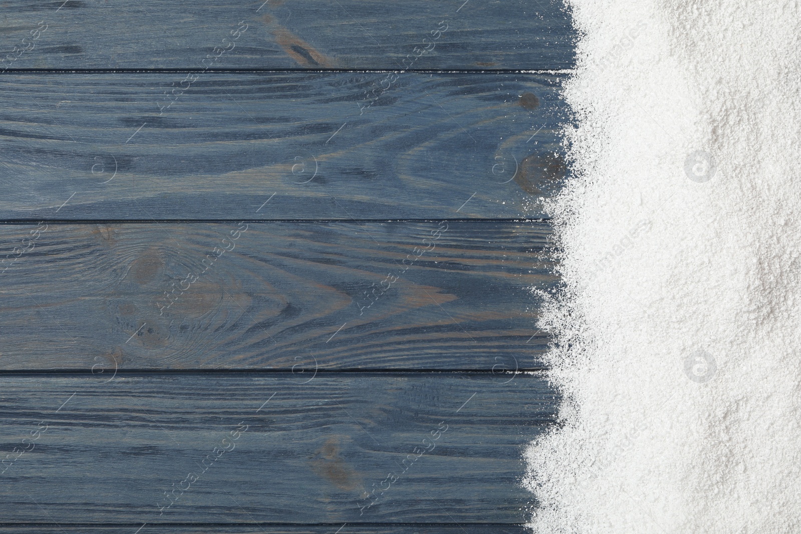 Photo of Artificial snow on blue wooden background, top view with space for text. Christmas decor