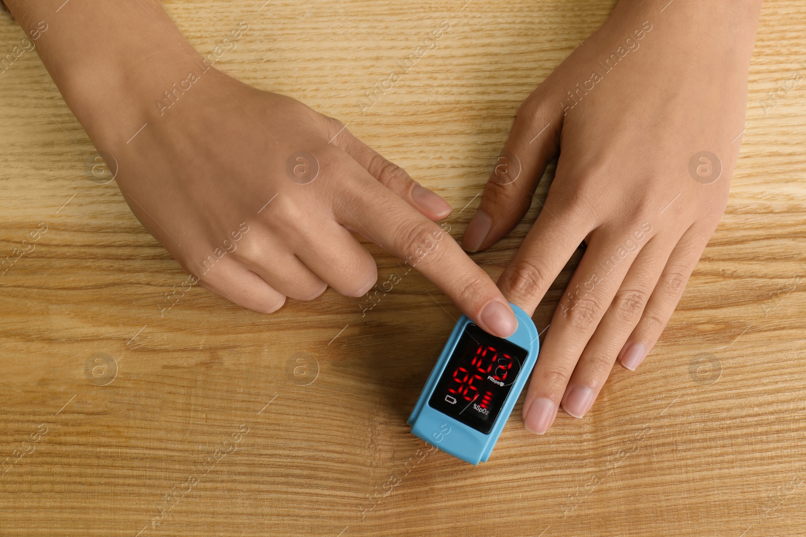 Man using pulse oximeter for oxygen level testing at wooden table, top view Photo of Man using pulse oximeter for oxygen level testing at wooden table, top view