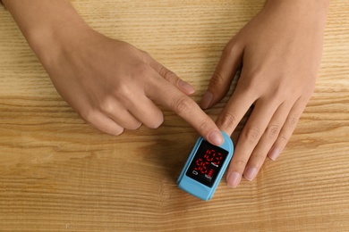 Man using pulse oximeter for oxygen level testing at wooden table, top view Photo of Man using pulse oximeter for oxygen level testing at wooden table, top view