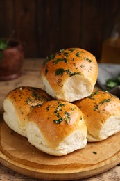 Traditional pampushka buns with garlic and herbs on wooden table, closeup Photo of Traditional pampushka buns with garlic and herbs on wooden table, closeup