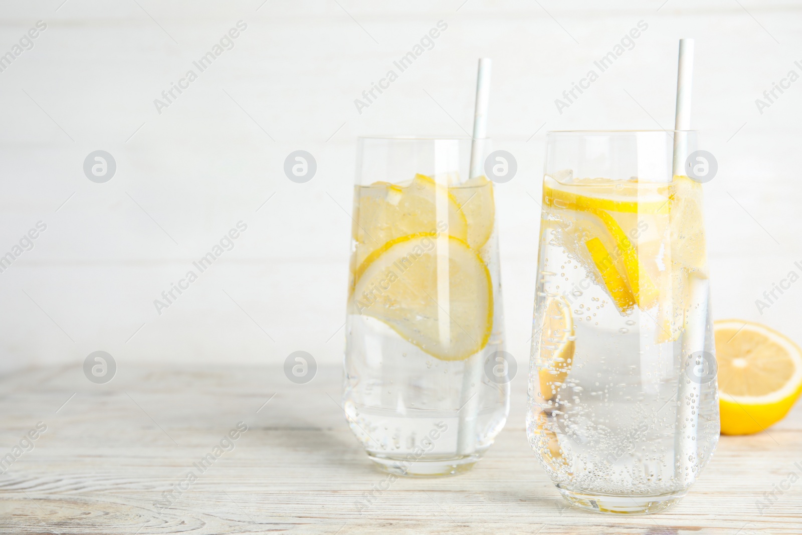 Soda water with lemon slices on white wooden table. Space for text Photo of Soda water with lemon slices on white wooden table. Space for text