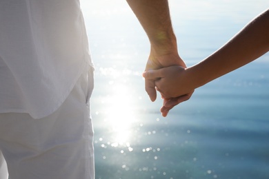 Couple holding hands together near river, closeup. Nature healing power Photo of Couple holding hands together near river, closeup. Nature healing power