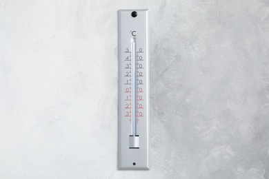 Weather thermometer hanging on light grey wall Photo of Weather thermometer hanging on light grey wall