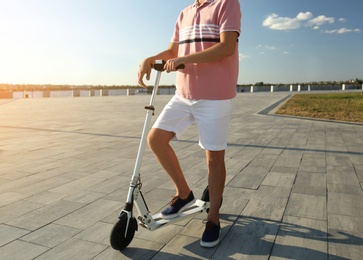 Man with modern kick scooter on waterfront, closeup Photo of Man with modern kick scooter on waterfront, closeup