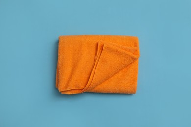 Folded orange beach towel on light blue background, top view Photo of Folded orange beach towel on light blue background, top view