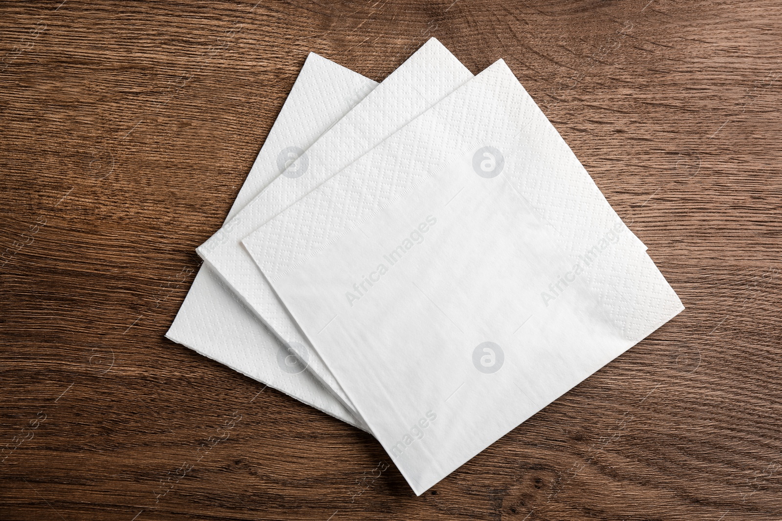 White clean paper tissues on wooden table, top view Photo of White clean paper tissues on wooden table, top view