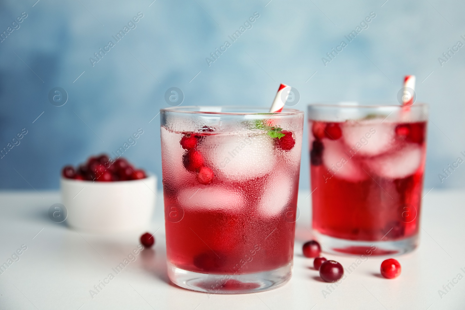 Tasty refreshing cranberry cocktail with mint on white table Photo of Tasty refreshing cranberry cocktail with mint on white table