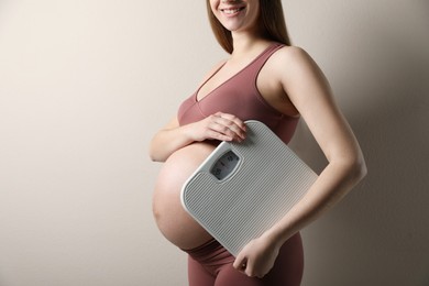 Pregnant woman with scales on beige background, closeup Photo of Pregnant woman with scales on beige background, closeup