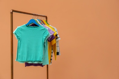 Photo of Rack with stylish children clothes on beige background. Space for text