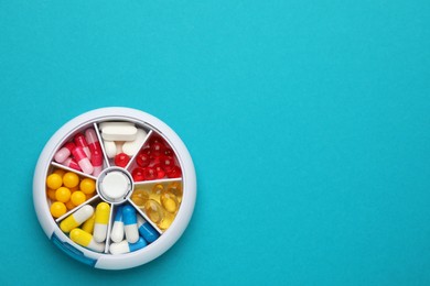 Plastic box with different pills on light blue background, top view. Space for text Photo of Plastic box with different pills on light blue background, top view. Space for text