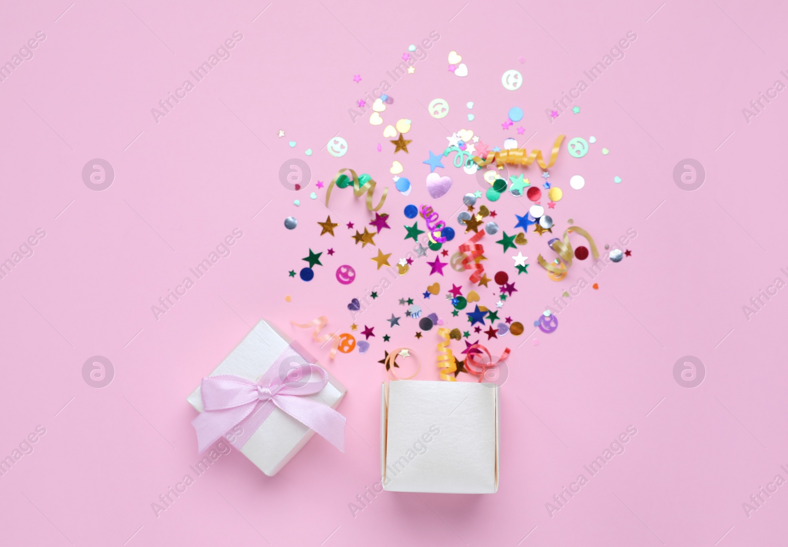 Shiny colorful confetti bursting out of box on pink background, top view Photo of Shiny colorful confetti bursting out of box on pink background, top view