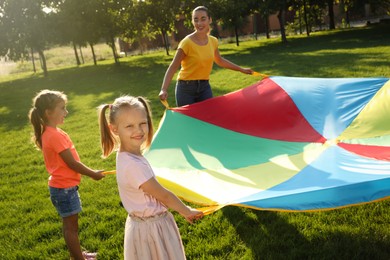 Group of children and teacher playing with rainbow playground parachute on green grass. Summer camp activity Photo of Group of children and teacher playing with rainbow playground parachute on green grass. Summer camp activity