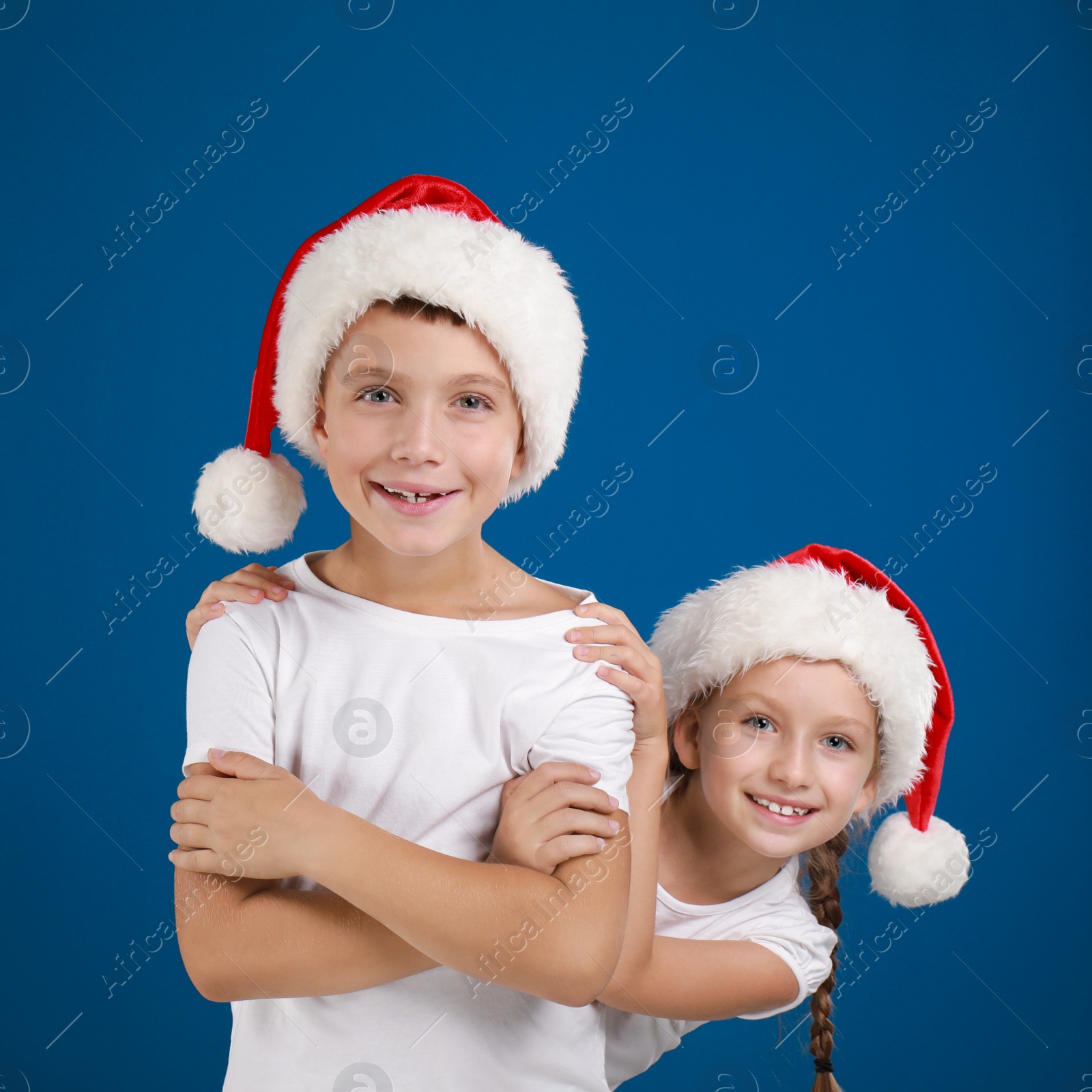 Happy little children in Santa hats on blue background. Christmas celebration Image of Happy little children in Santa hats on blue background. Christmas celebration